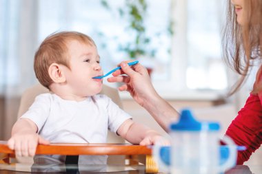 Mutfakta yemek kaşığı ile onun elini tutarak bebek beslenme anne. Sağlıklı bebek maması. Bir çocuğun duygularını yerken