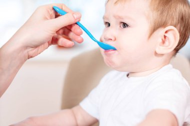 Bir kaşık yulaf lapası mutfakta elini tutarak bebek beslenme anne. Duygular bir çocuğun sağlıklı yemek yerken