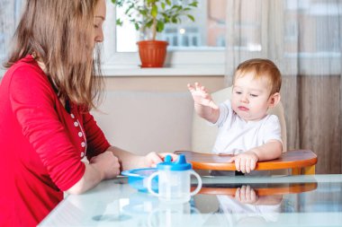 Mutfakta yemek kaşığı ile onun elini tutarak bebek beslenme anne. Sağlıklı bebek beslenme. Bir çocuğun duygularını yerken