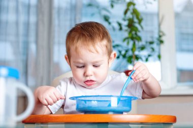 Bir kaşık kendini mutfakta çocuklar masada yemek öğrenme küçük oğlu. Sağlıklı bebek maması kavramı