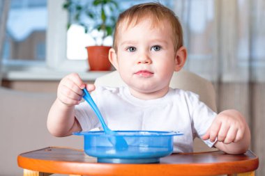 Bir kaşık kendini mutfakta çocuklar masada yemek öğrenme küçük oğlu. Sağlıklı bebek maması kavramı