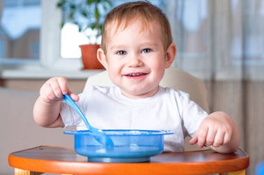 Bir kaşık kendini mutfakta çocuklar masada yemek öğrenme küçük oğlu. Sağlıklı bebek maması kavramı