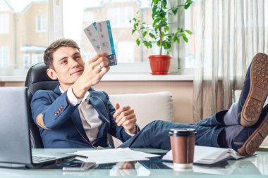 Genç adam kazandı biletleri tutuyor. Yolculuk için bekleyen bir sevinç. Office tatil kavramı