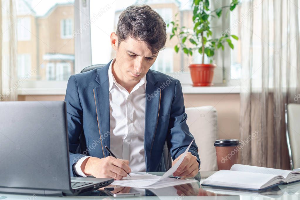Man businessman sitting at the table signing documents in the office. Concept of registration of transactions and work with securities