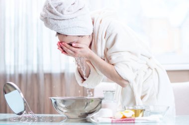 Sabah yüzünü su ile yıkama başında bir havlu ile güzel genç kadın. Kavramı hijyen ve evde cilt bakımı