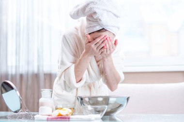 Sabah yüzünü su ile yıkama başında bir havlu ile güzel genç kadın. Kavramı hijyen ve evde cilt bakımı