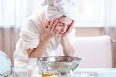 Yıkama ve su ile yüzünü sabah serinletici başında bir havlu ile güzel genç kadın. Kavramı hijyen ve evde cilt bakımı