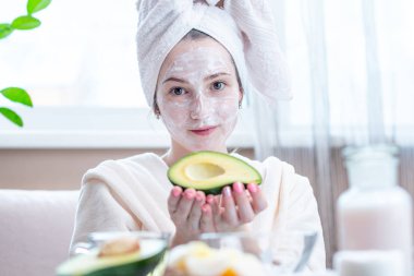 Kozmetik doğal avokado maskesi yüzünde güzel mutlu genç kadın. Kavram cilt bakımı ve Spa uygulamaları evde