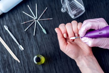 Kadın manikürcü freze kesici araçlar arka plan üzerinde kullanarak bir profesyonel manikür donanım yapıyor. Karanlık üstten görünüm