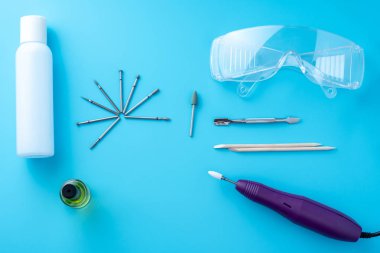 Profesyonel donanım manikür mavi bir arka plan üzerinde kozmetik araçlar kümesi. Freze kesici, Gözlük, manikür temizleyici, üstten görünüm