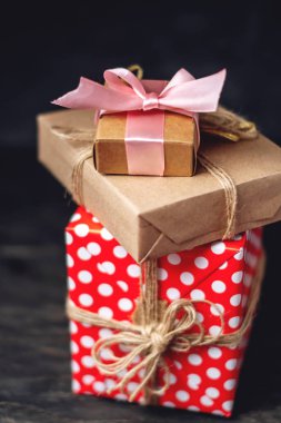 Tatil hediye kutuları, kağıt ve koyu ahşap arka plan üzerinde kırmızı lekeli işçiliği Paketli. Güzel hediyeler kartlarla kavramı