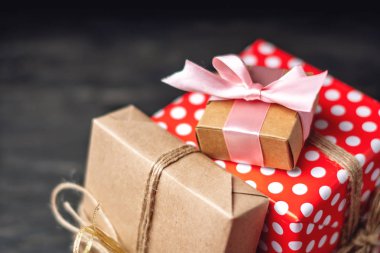 Tatil hediye kutuları, kağıt ve koyu ahşap arka plan üzerinde kırmızı lekeli işçiliği Paketli. Güzel hediyeler kartlarla kavramı