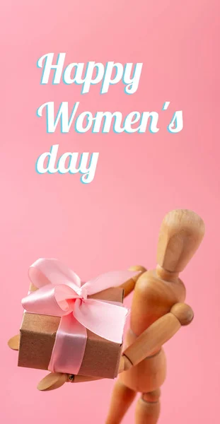 ピンクの背景に贈り物を保持する木のおもちゃモデル 本文概念休日の縦型カードの幸せな女性の日 — ストック写真
