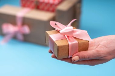 Kadınların elleri tutan mavi zemin üzerine pembe kurdele ile Kraft kağıt hediye kutusunda paketlenmiştir. Sevgililer günü ve kadınlar günü kavramı tatil kartı