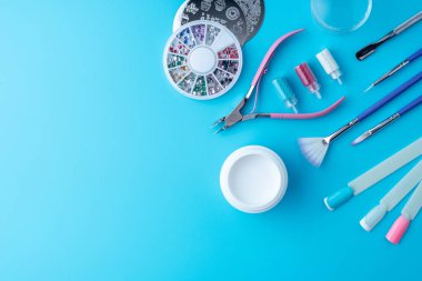 Profesyonel manikür, tırnak bakım ve mavi bir arka plan üzerinde güzel tasarımlar oluşturmak için kozmetik araçlar kümesi. Üstten görünüm. Metin için bir yer ile kart için kompozisyon