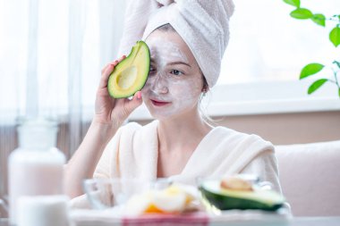 Kozmetik doğal avokado maskesi yüzünde güzel mutlu genç kadın. Kavram cilt bakımı ve Spa uygulamaları evde