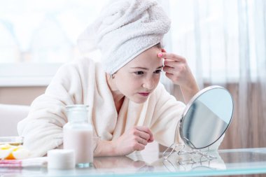 Onun bedenine girdim bir ayna bakarak başında bir havlu ile güzel mutlu genç kadın. Kavramı zamanında hijyen ve evde cilt bakımı
