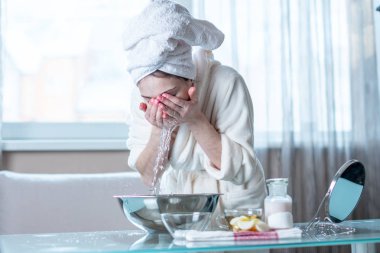 Sabah yüzünü su ile yıkama başında bir havlu ile güzel genç kadın. Kavramı hijyen ve evde cilt bakımı