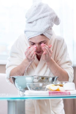 Yıkama ve su ile yüzünü sabah serinletici başında bir havlu ile güzel genç kadın. Kavramı hijyen ve evde cilt bakımı