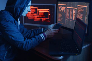 Bir erkek hacker'ı olan ekranlar neon ışık altında karanlıkta arka plan üzerinde bir sistem güvenlik duvarı kesmek bir siber suç işlemekle program kodu yazarak bir başlık. Siber güvenlik kavramı