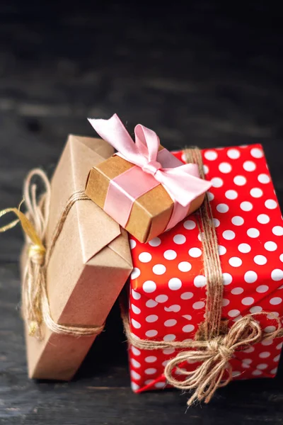 Holiday gift boxes Packed in crafting paper and red polka dots on dark wooden background. The concept of beautiful cards with gifts