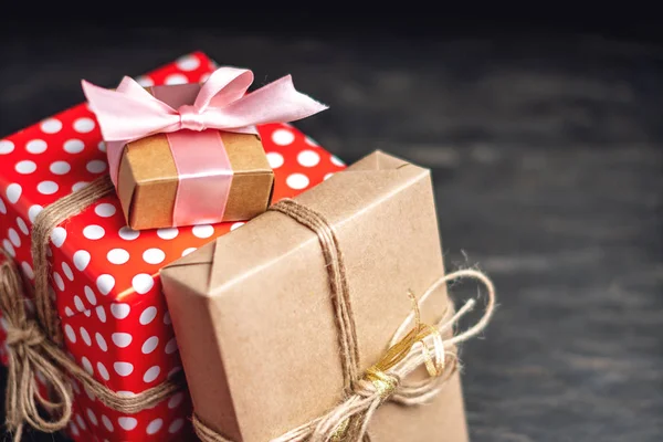 Tatil hediye kutuları, kağıt ve koyu ahşap arka plan üzerinde kırmızı lekeli işçiliği Paketli. Güzel hediyeler kartlarla kavramı