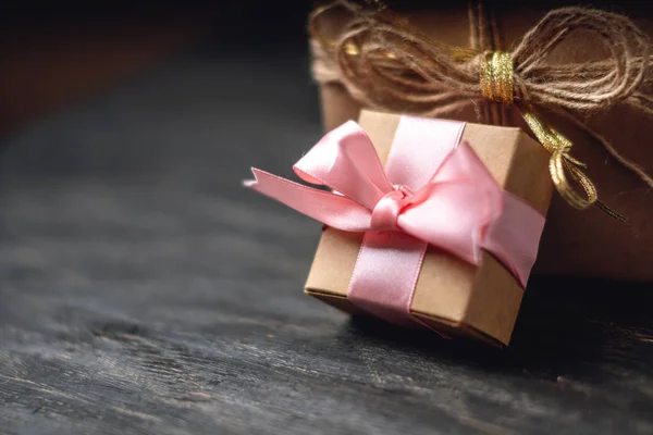 Holiday gift box Packed in crafting paper on dark wooden background. The concept of beautiful cards with gifts and place for text