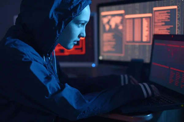 女孩黑客在一个引擎盖打字程序代码 同时实施网络犯罪黑客在黑暗中的屏幕背景下的系统防火墙在霓虹灯下 网络安全概念 — 图库照片