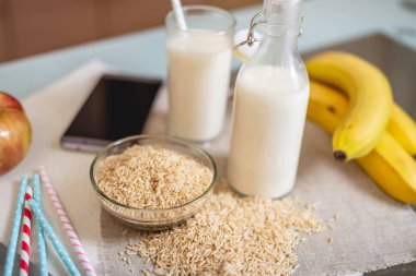 Bir bardak Bardak pirinç sütü ve masada pirinç dağınık taneleri ile meyve. Diyet sağlıklı vejetaryen ürün