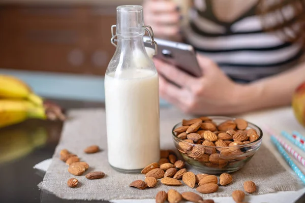 Mujer Bebiendo Leche Almendras Orgánica Sosteniendo Teléfono Mano Cocina Botella — Foto de Stock