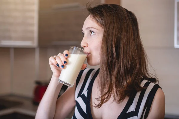 Mutfakta cam bardak tutan pipetlerden organik yulaf sütü içen kadın. Diyet sağlıklı vejetaryen ürün