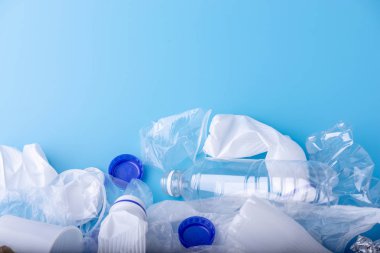 Bir yığın içinde temiz plastik çöp kullanılır. Mavi arka planda şişeler ve çantalar. Çevre kirliliği ve atık ayıklama kavramı