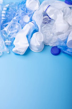 Bir yığın içinde temiz plastik çöp kullanılır. Mavi arka planda şişeler ve çantalar. Çevre kirliliği ve atık ayıklama kavramı