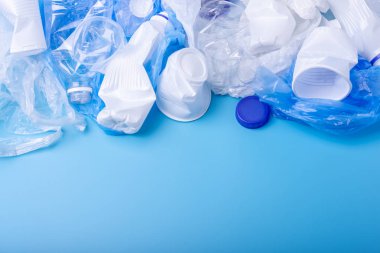 Bir yığın içinde temiz plastik çöp kullanılır. Mavi arka planda şişeler ve çantalar. Atık sıralama kavramı