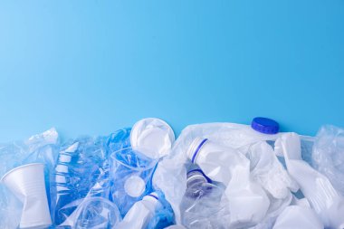 Bir yığın içinde temiz plastik çöp kullanılır. Mavi arka planda şişeler ve çantalar. Atık sıralama kavramı