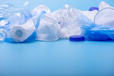 Bir yığın içinde temiz plastik çöp kullanılır. Mavi arka planda şişeler ve çantalar. Atık sıralama kavramı