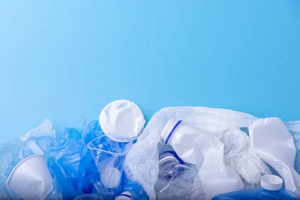 Used clean plastic garbage in a pile. Bottles and bags on blue background. Concept of environmental pollution and waste sorting