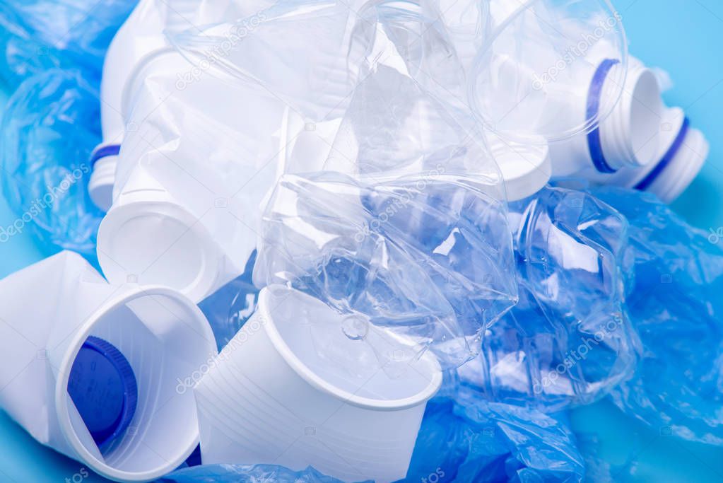 Used plastic garbage in a pile. Bottles and bags on blue background. Concept of environmental pollution and waste sorting