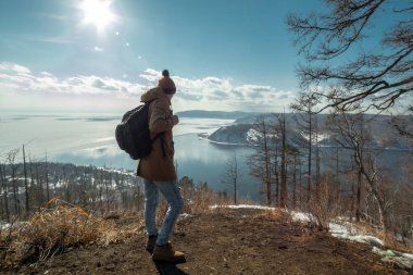 Adam turist gezgin bir dağ üzerinde duruyor ve Baykal Gölü güzel görünümüne bakar. Kış manzarası.