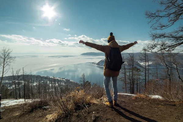 Viajante fica em uma montanha e olha para a bela vista do lago Baikal. Paisagem inverno . — Fotografia de Stock