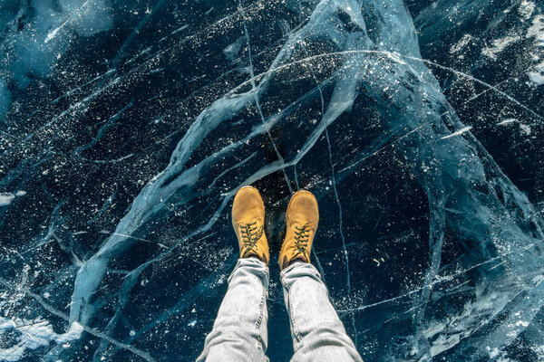 Men's yellow shoes on the pure blue ice of lake Baikal. Concept tourism and travel to famous places of nature