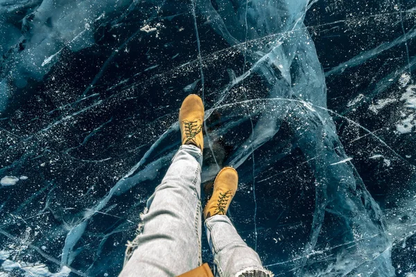 Zapatos amarillos de hombre en el hielo azul puro del lago Baikal. Concepto de turismo y viajes a lugares famosos de la naturaleza — Foto de Stock