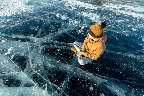 Traveler meditates sitting in Lotus position on pure ice of lake Baikal. Travel to beautiful places of nature — Stock Photo, Image