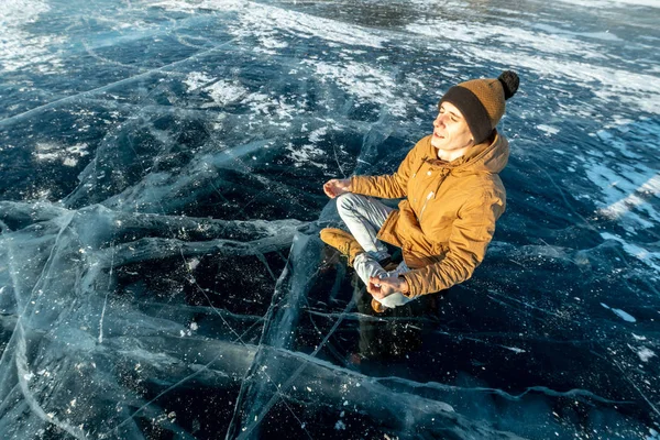 Viajante medita sentado na posição de Lótus no gelo puro do lago Baikal. Viajar para lugares bonitos da natureza — Fotografia de Stock