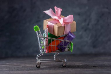 Karanlık bir arka plan üzerinde alışveriş sepetigünlük alımları ve hediyeler. Mağazalarda ve süpermarketlerde alışveriş