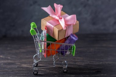 Karanlık bir arka plan üzerinde alışveriş sepetigünlük alımları ve hediyeler. Mağazalarda ve süpermarketlerde alışveriş