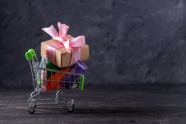 Karanlık bir arka plan üzerinde alışveriş sepetigünlük alımları ve hediyeler. Mağazalarda ve süpermarketlerde alışveriş