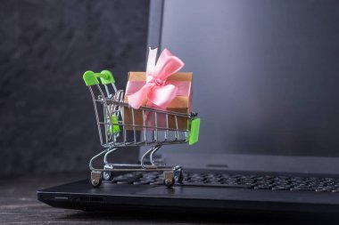 Karanlık bir arka plan üzerinde dizüstü klavye alışveriş sepeti günlük alışveriş. Çevrimiçi mağazalarda alışveriş