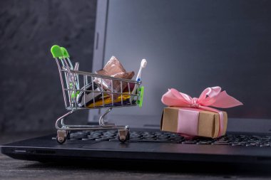 Dizüstü bilgisayar klavyesindeki alışveriş sepetinde günlük alışveriş ler ve hediyeler. Çevrimiçi mağazalarda alışveriş