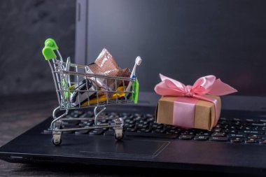 Dizüstü bilgisayar klavyesindeki alışveriş sepetinde günlük alışveriş ler ve hediyeler. Çevrimiçi mağazalarda alışveriş
